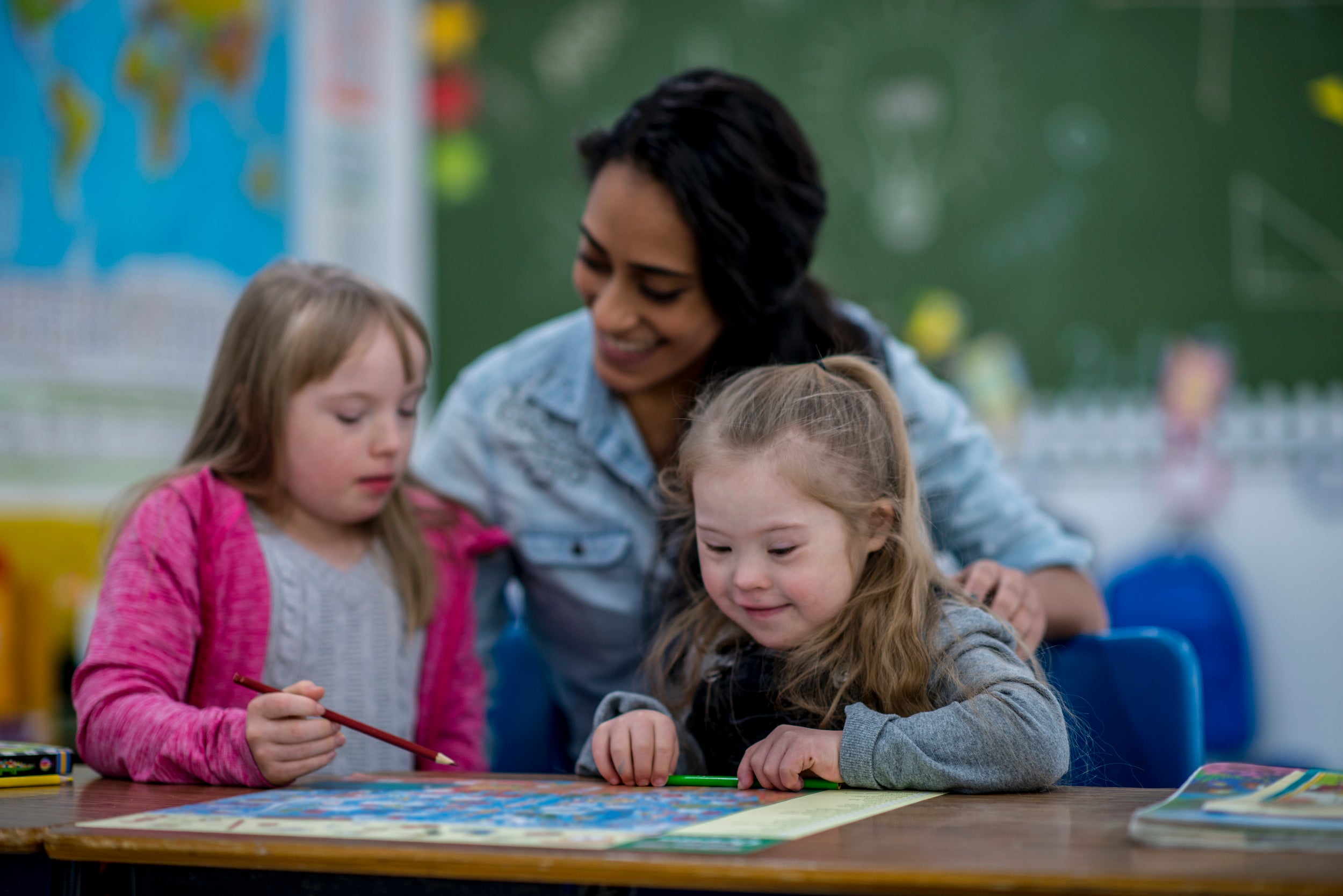 woman teacher helping two students with drawing