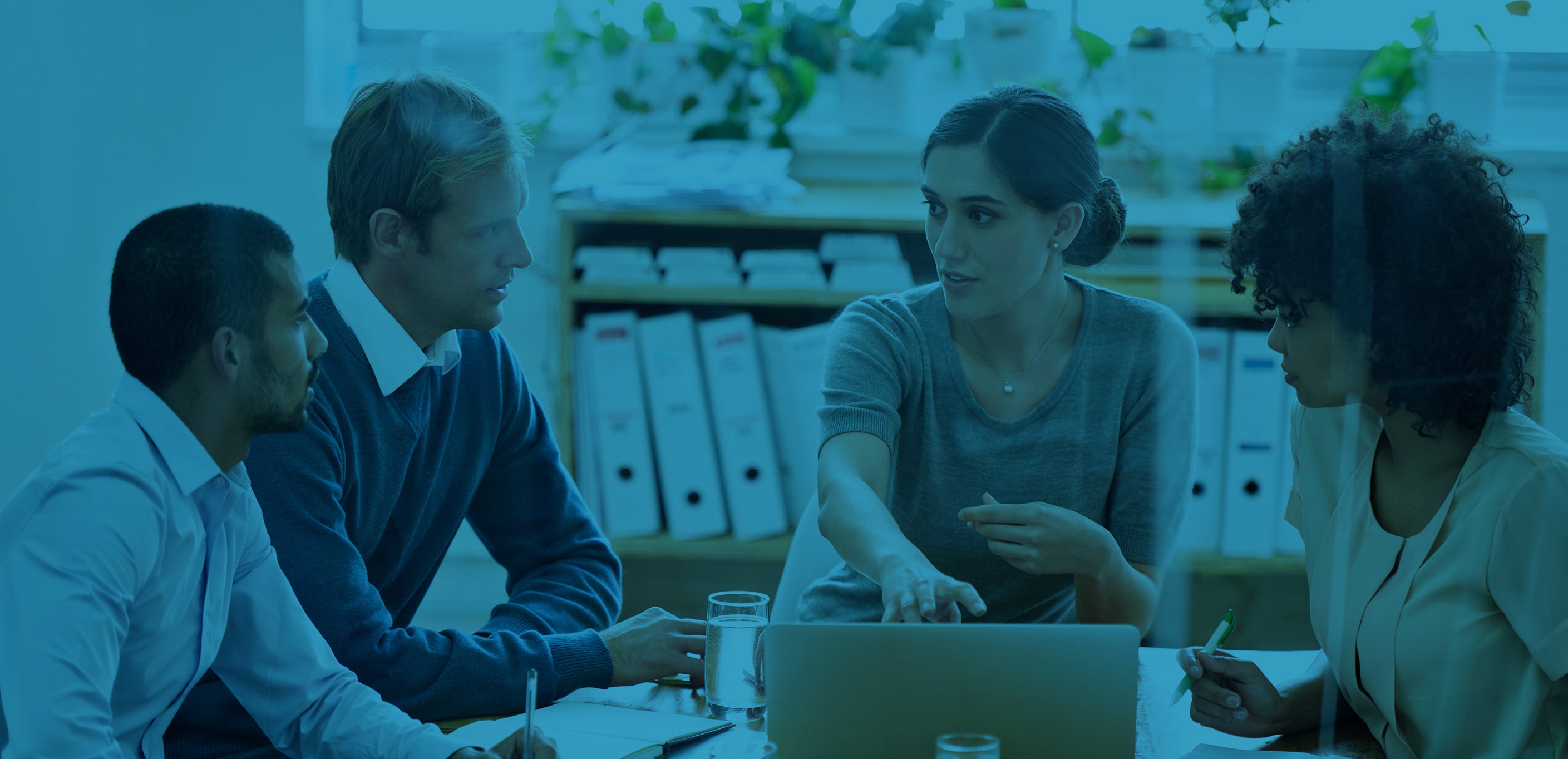 woman pointing at laptop and talking to group