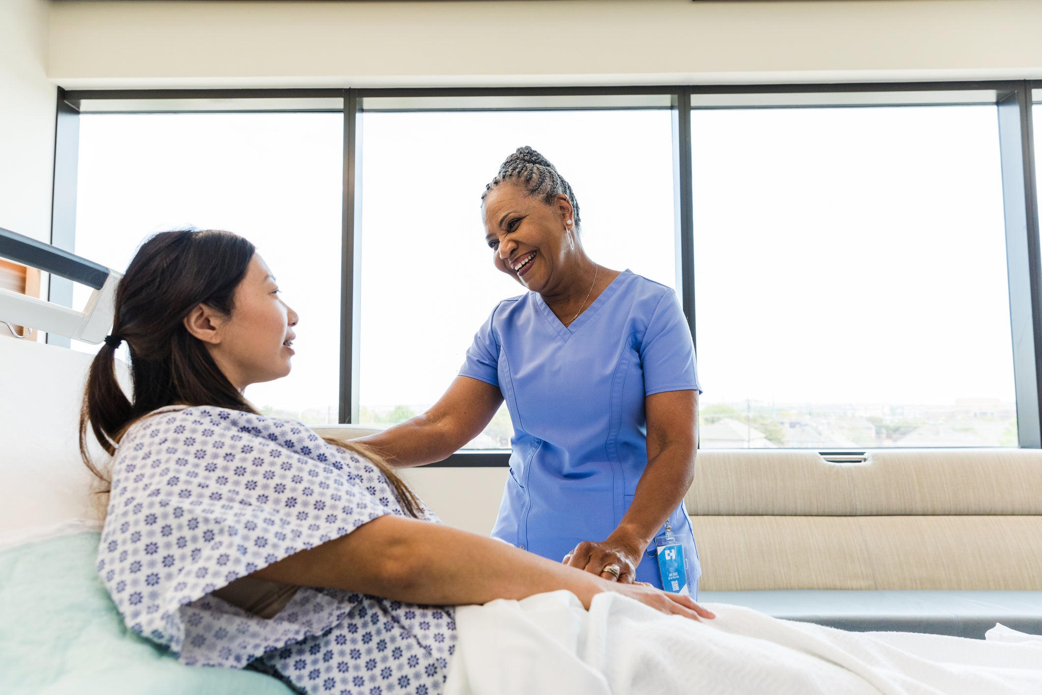Nurse talking to patient on bed