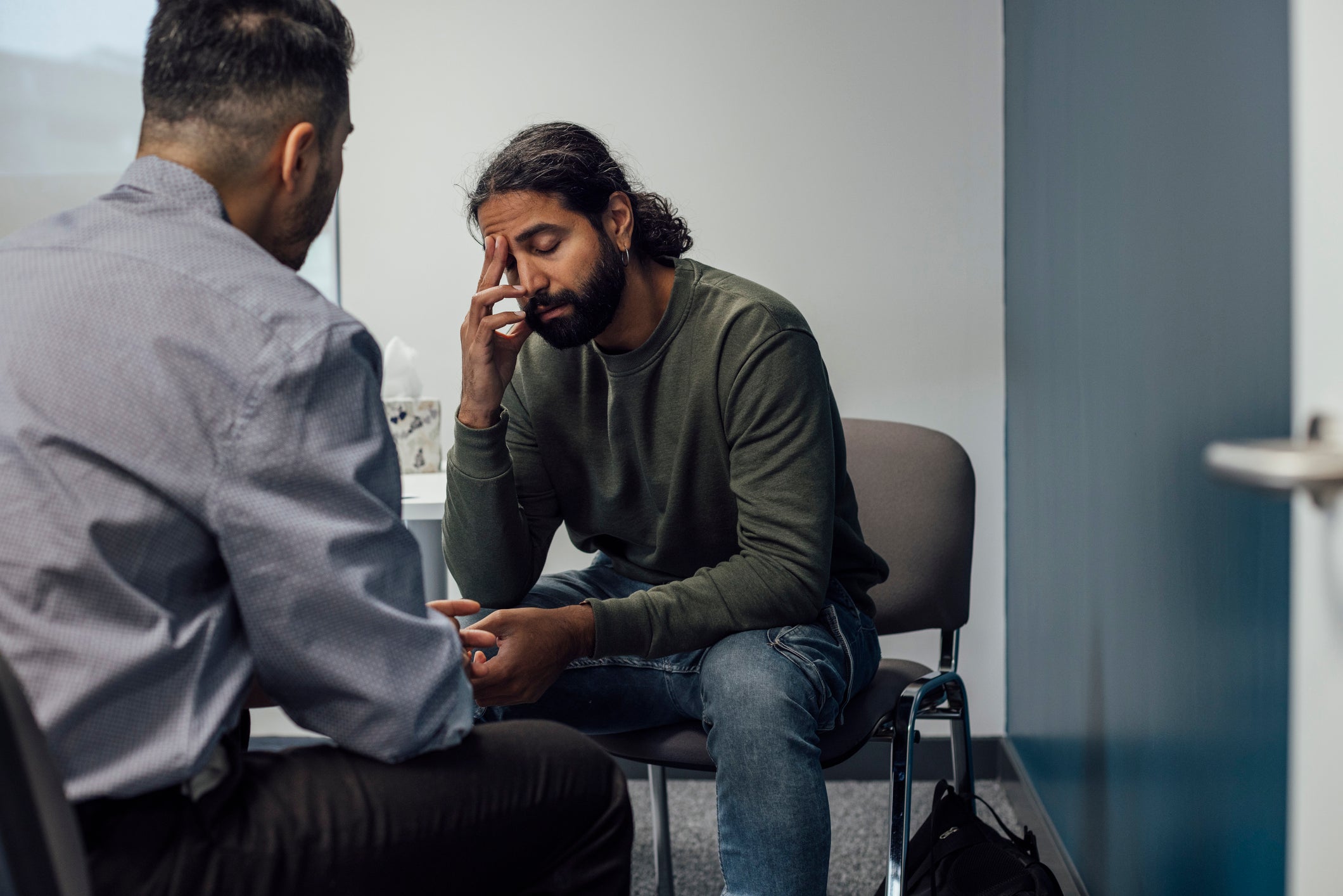 patient with hand on forehead talking with therapist