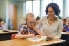 woman teacher helping student at desk