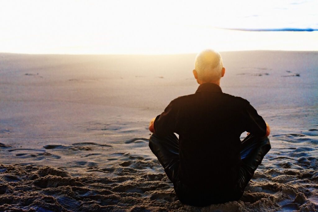 man meditating on beach