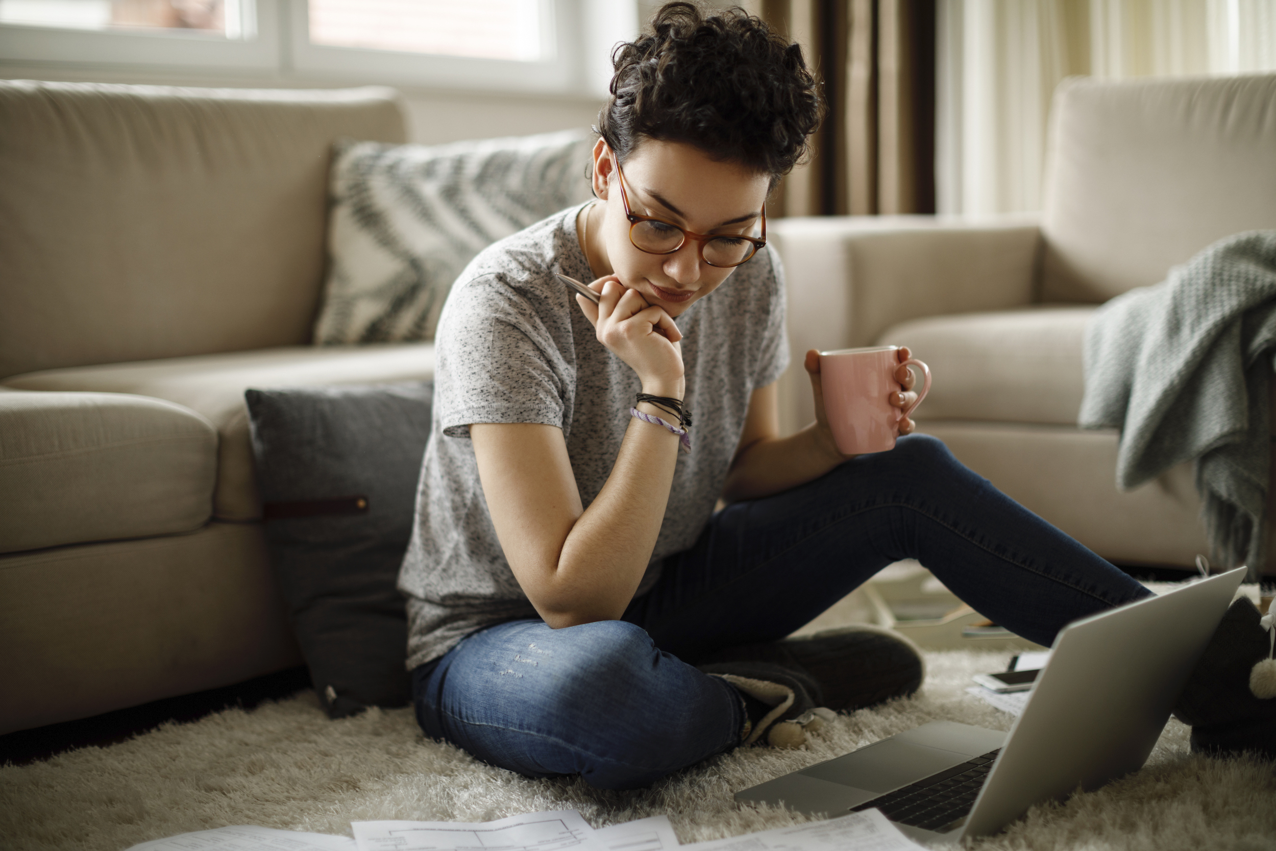 woman looking at laptop holding coffee