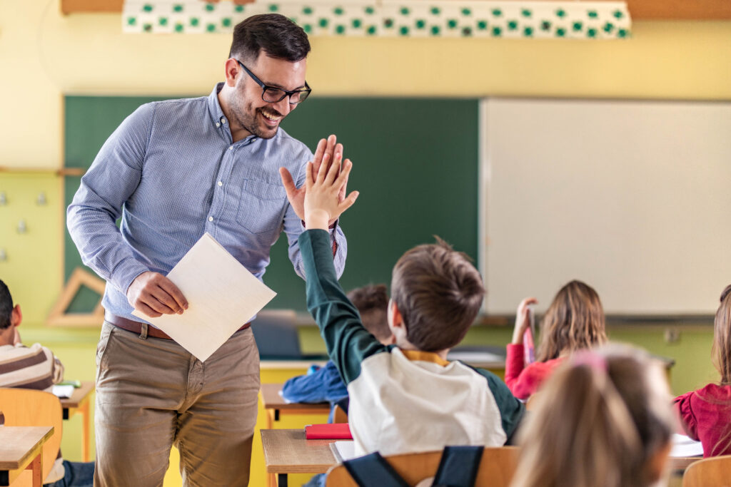 happy teacher and schoolboy giving each other high five