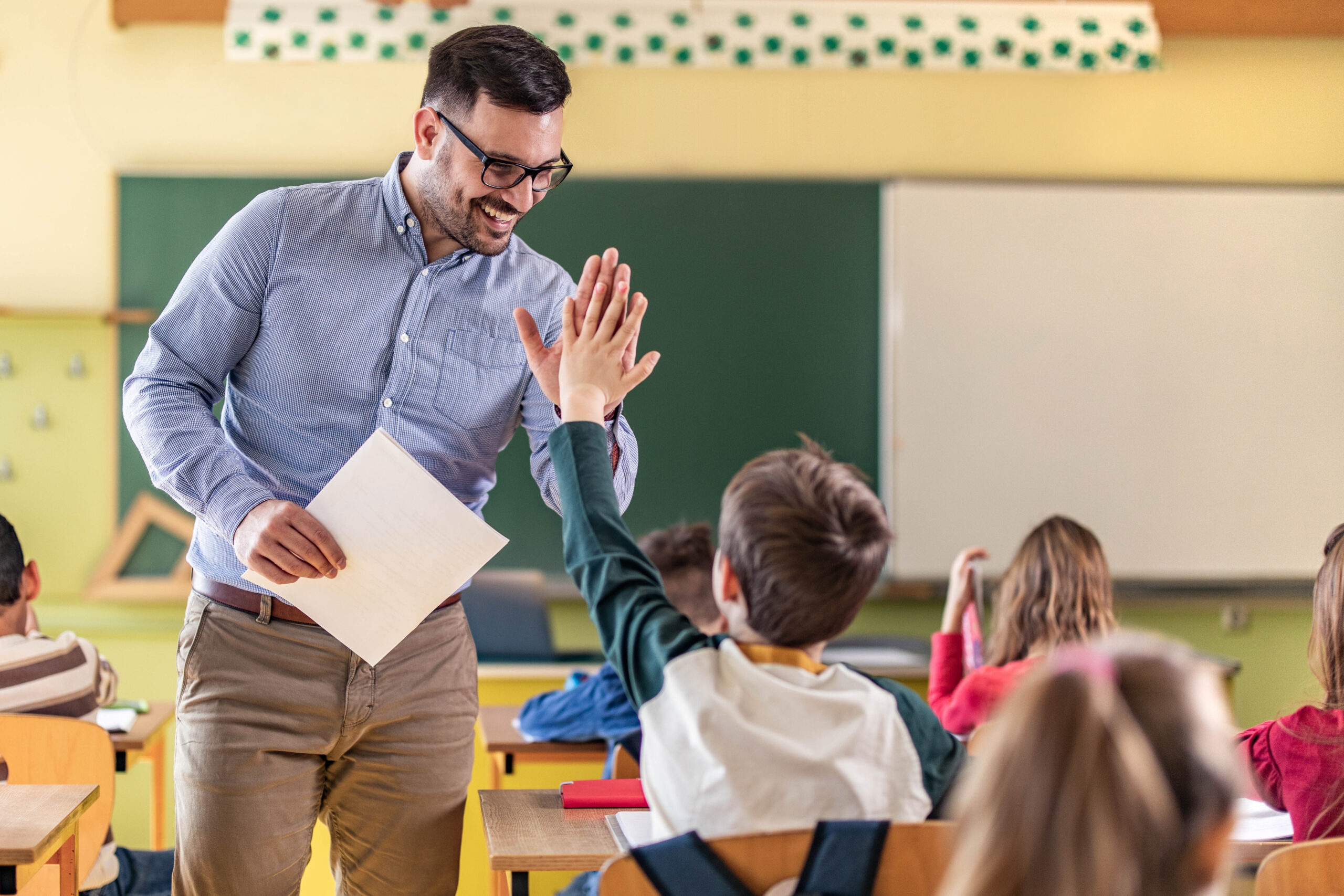 happy teacher and schoolboy giving each other high five
