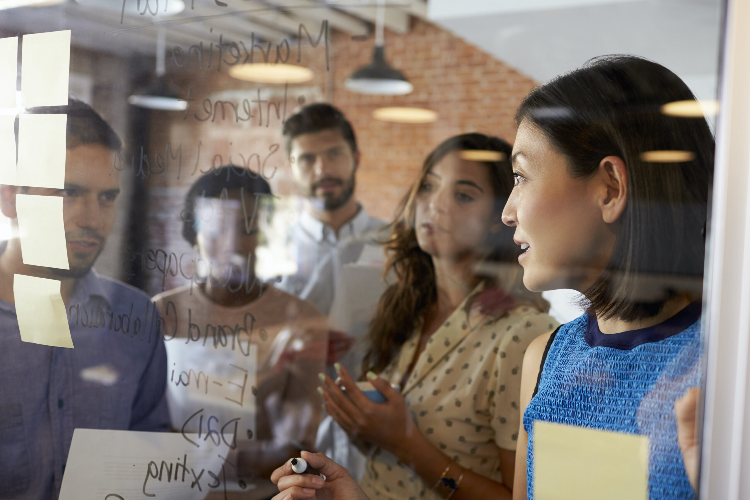 Businesswoman Writing Ideas On Glass Screen During Meeting