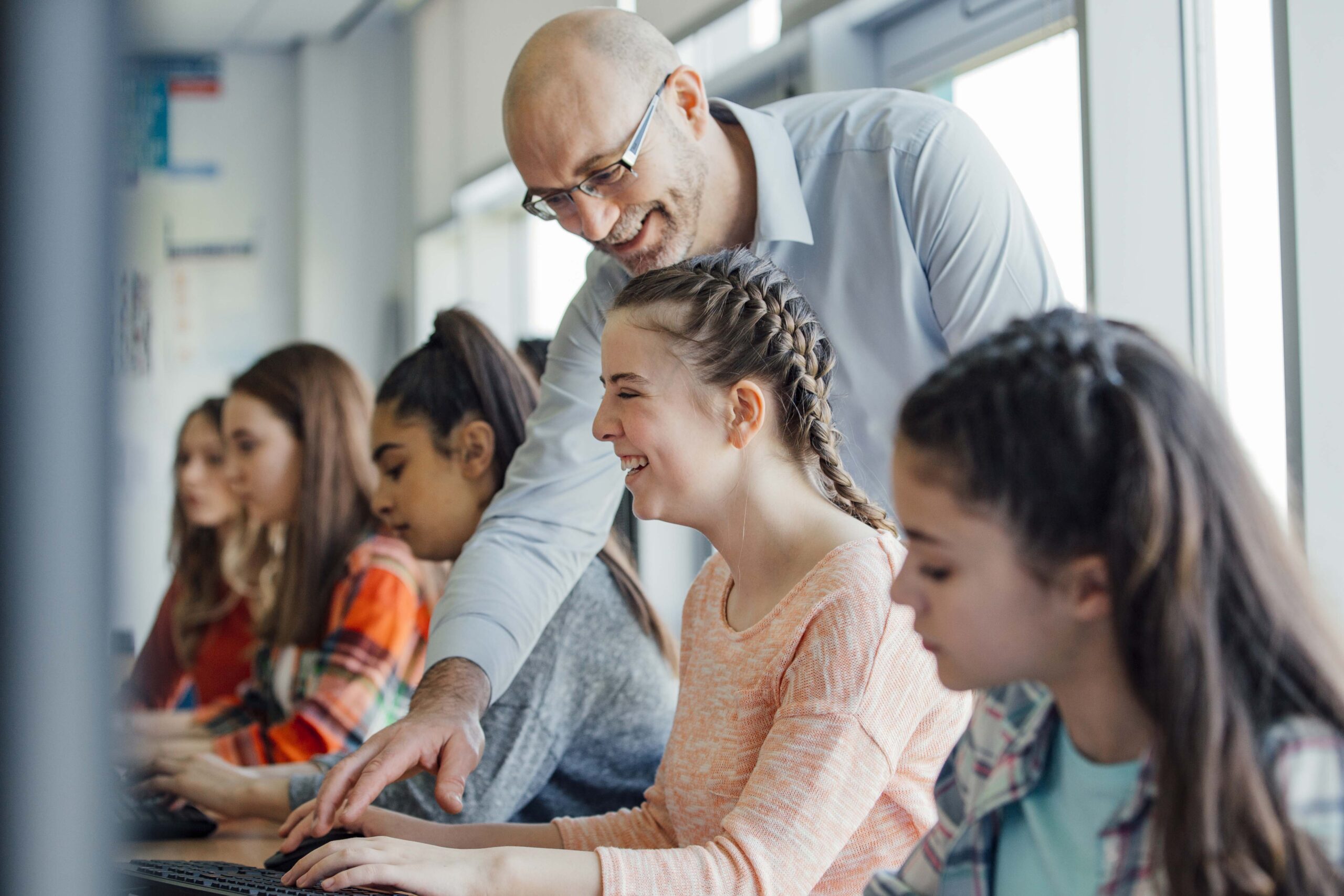 male teacher helping student at computer
