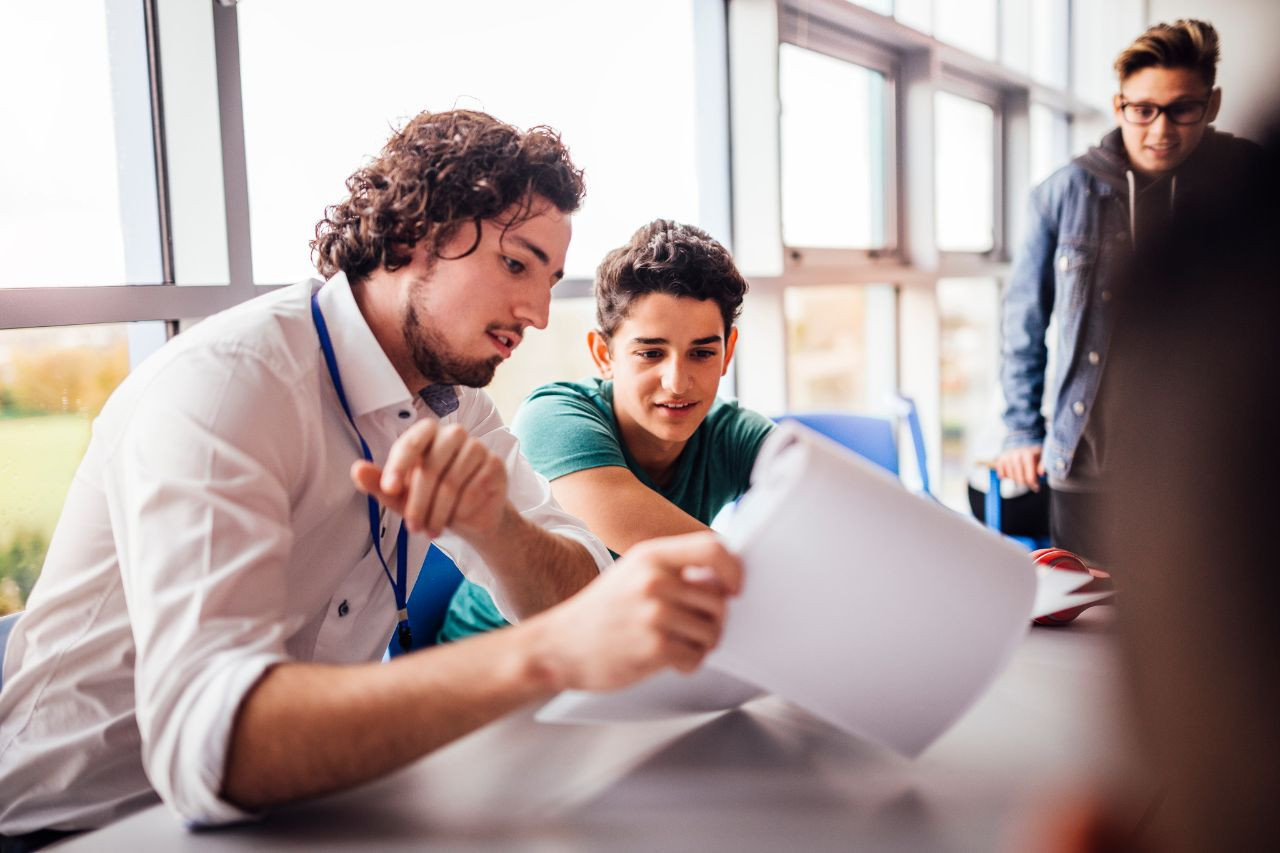 male teacher with secondary teaching certificate discussing to a student