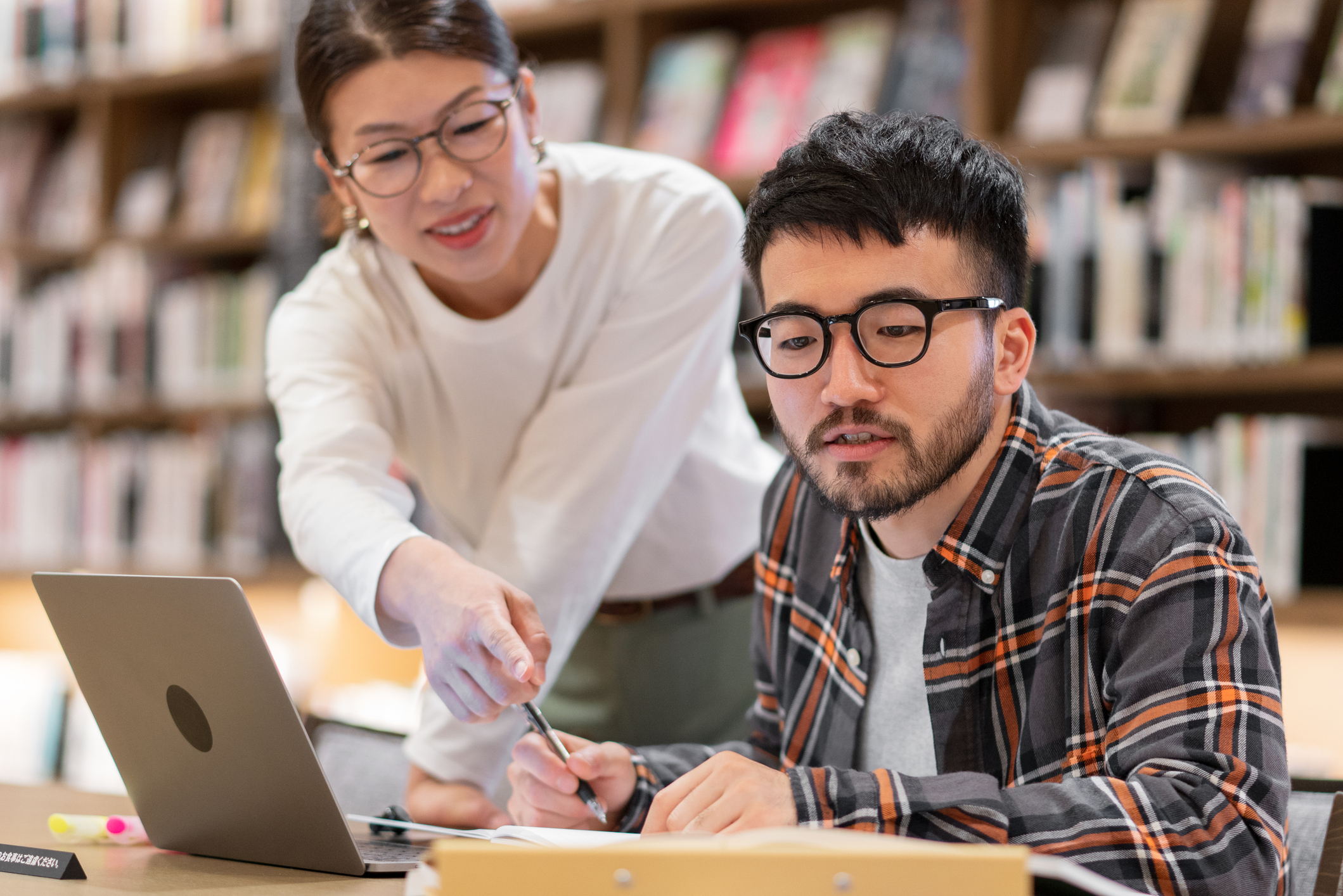 Female helping male student study looking at computer