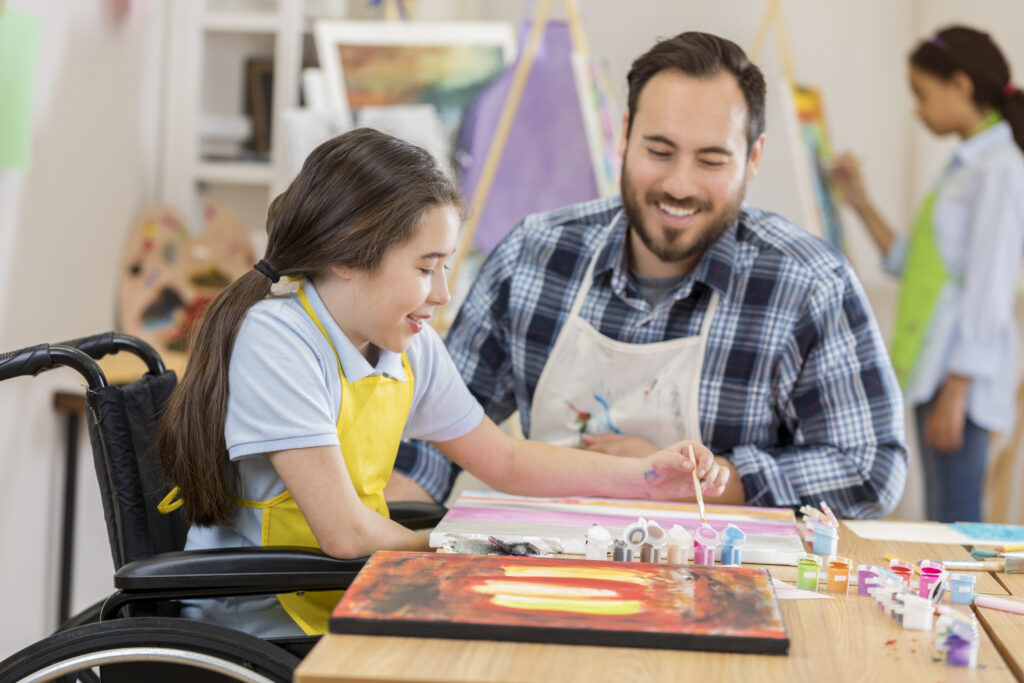 special education teacher teaching girl to paint