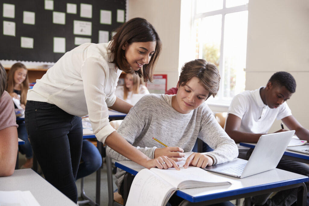 high school teacher showing student something in notebook