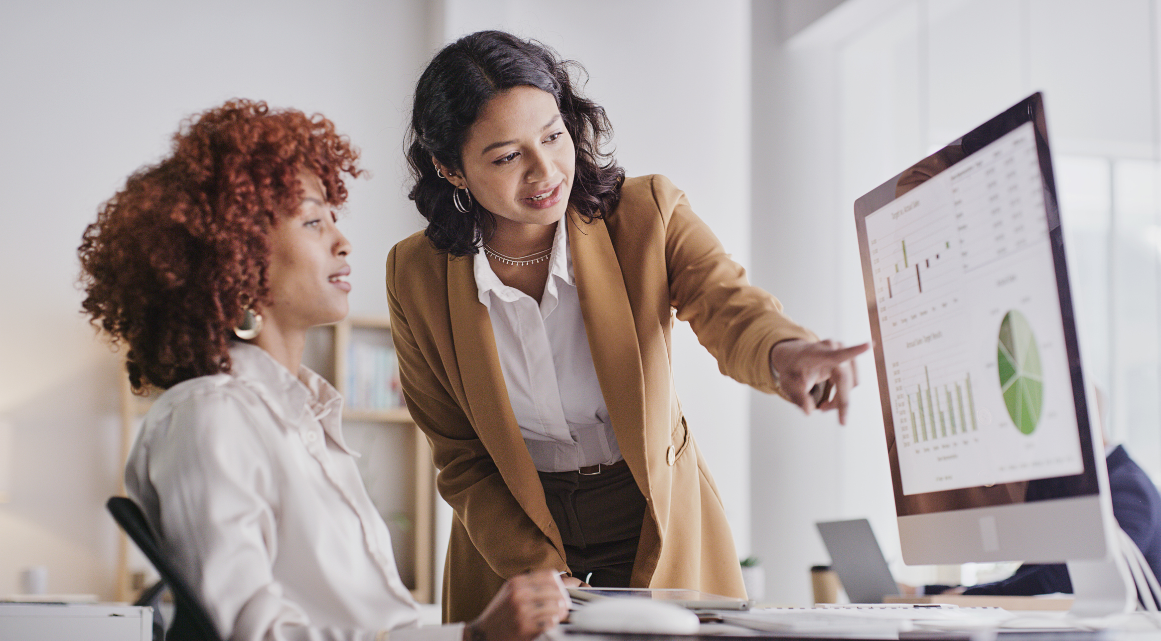 woman showing another woman a computer with data