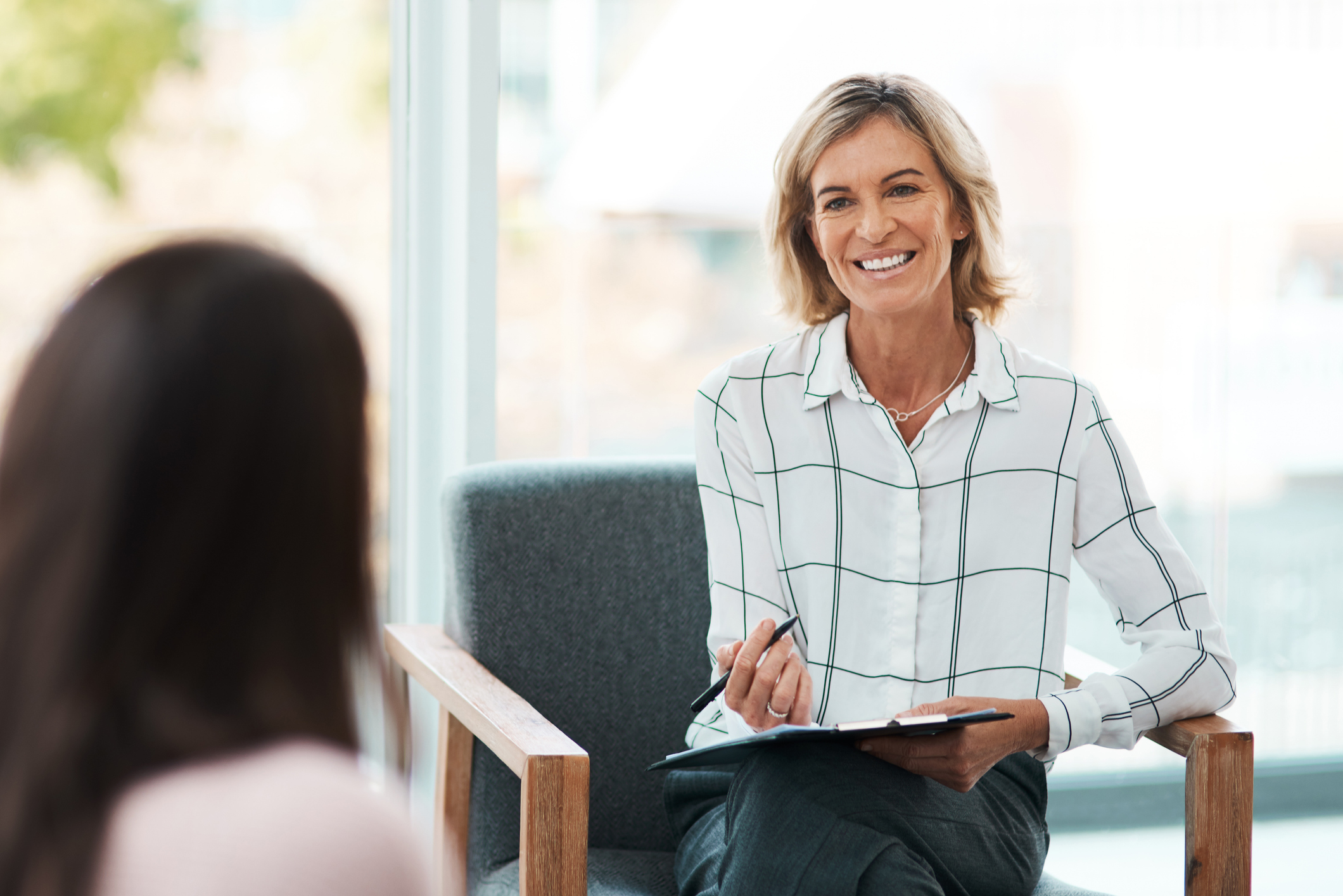 woman with clipboard listening to another woman