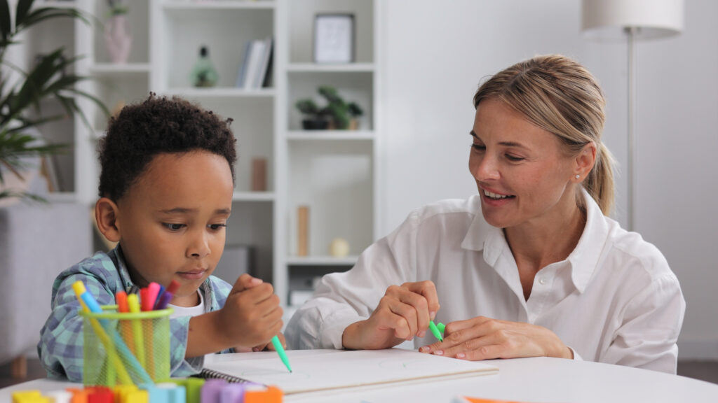 woman watching child draw on paper