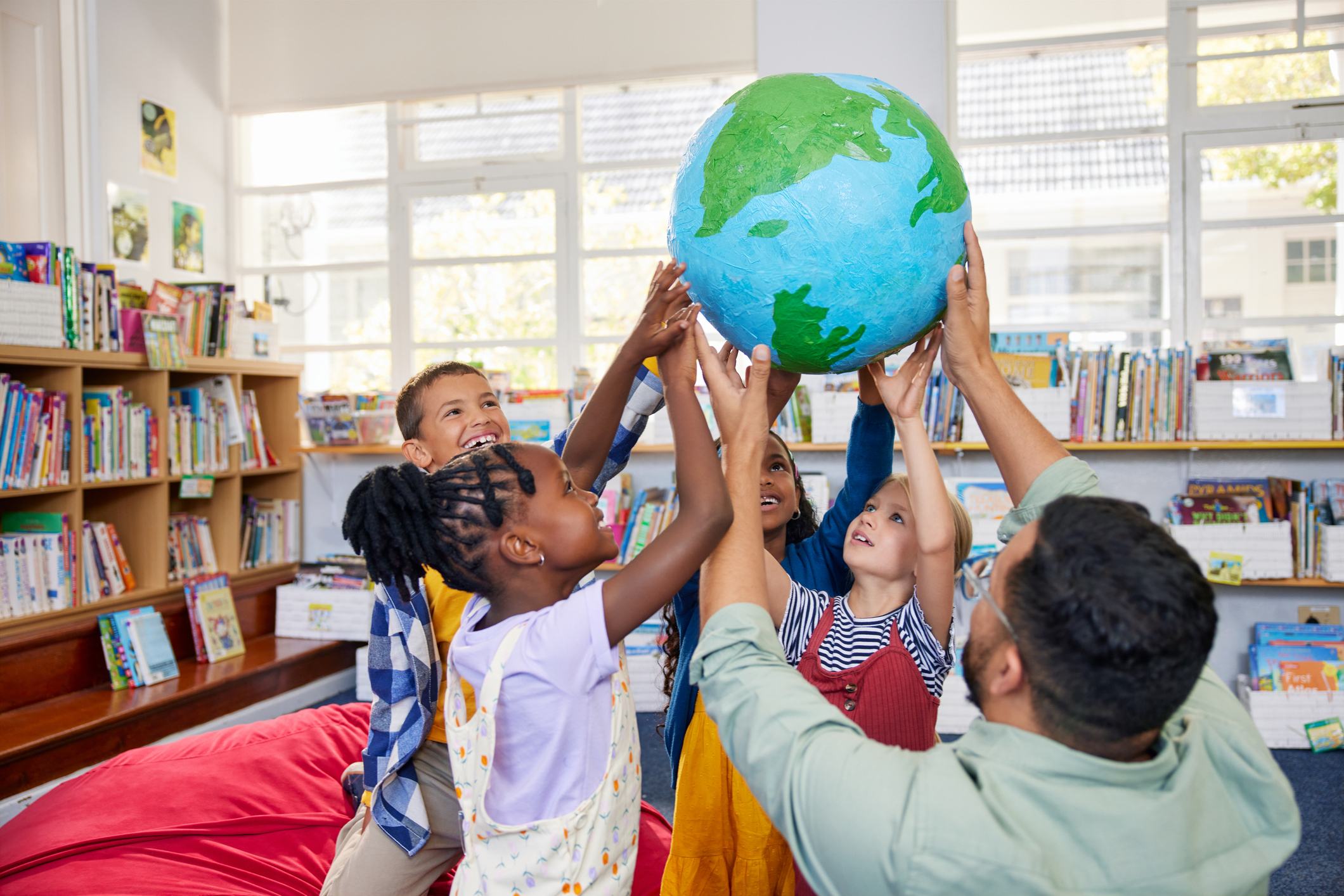 students and teacher holding up a globe