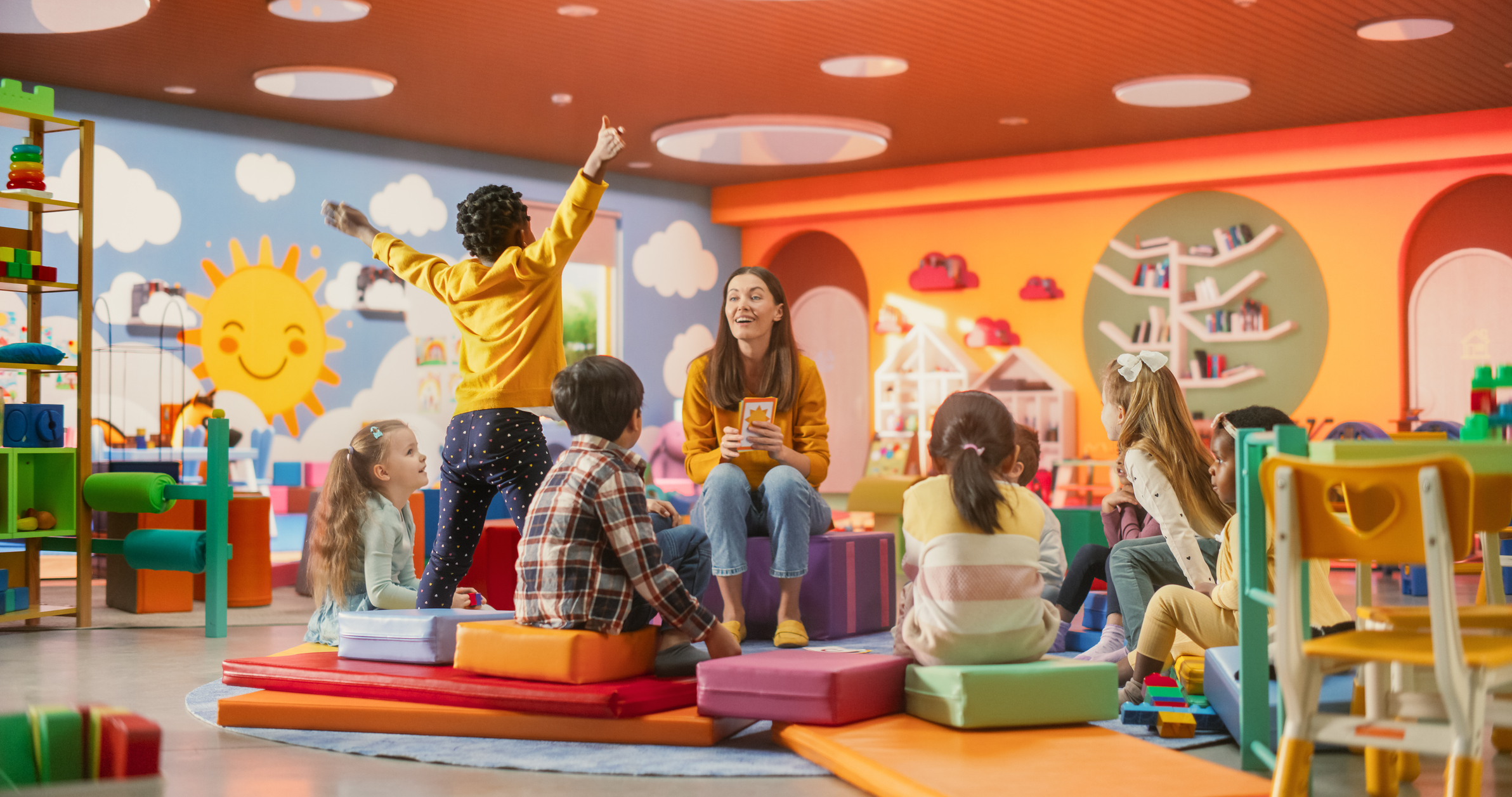 Kindergarten teacher with students in colorful classroom