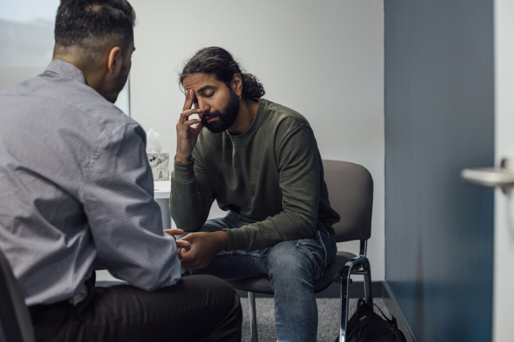 patient with hand on forehead talking with therapist