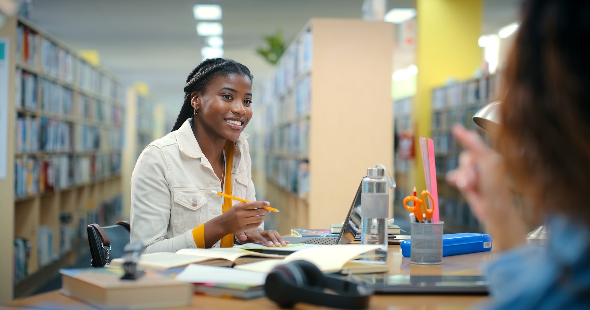 Conversation, students and women in library, education and smile with knowledge. Friends, university and girls with scholarship, learning and teamwork for project, assignment and advice for test