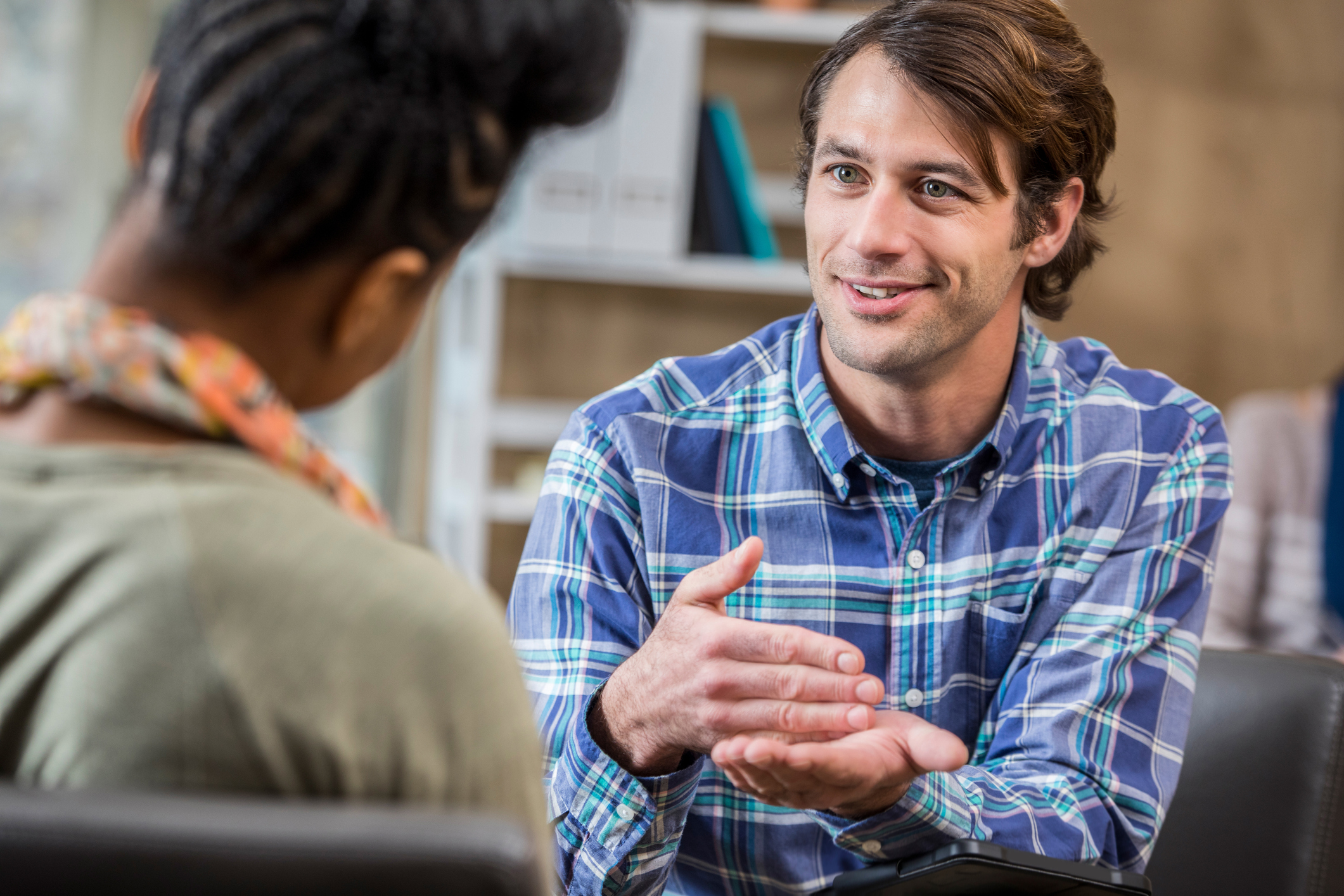 A man in a blue plaid shirt talking to a woman