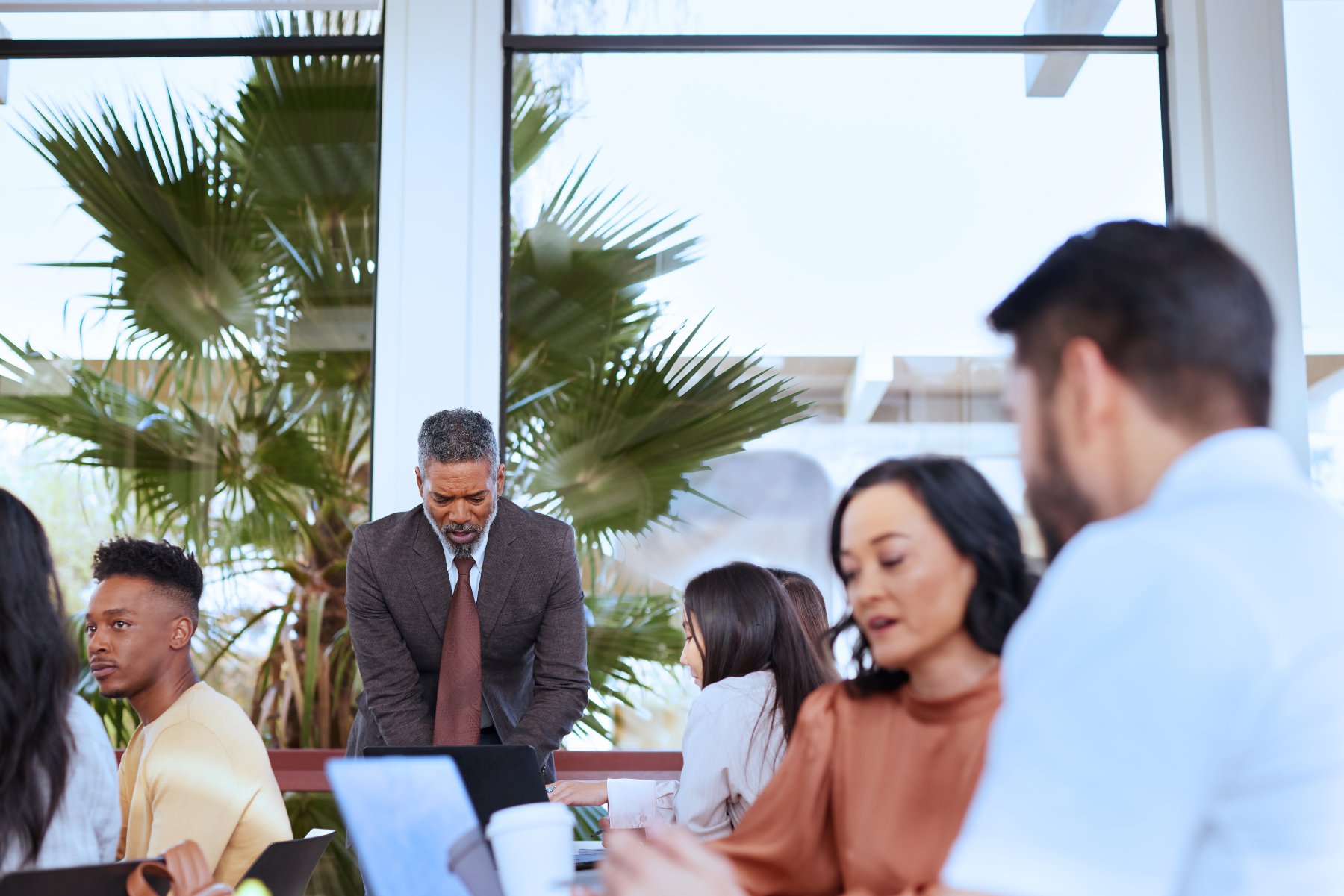 A professor speaking to a group of people sitting around a table