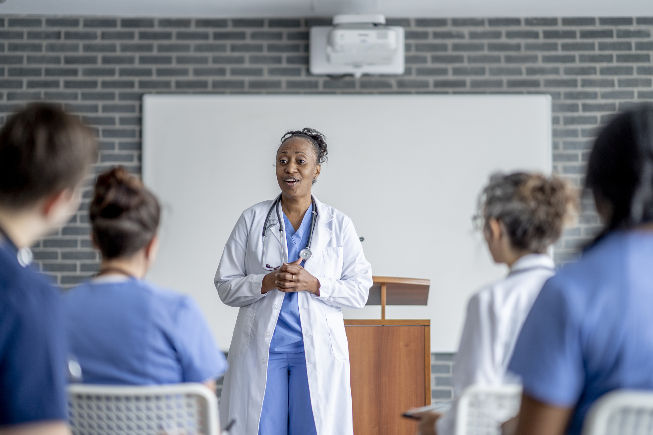 A woman in a white coat standing in front of a group of people