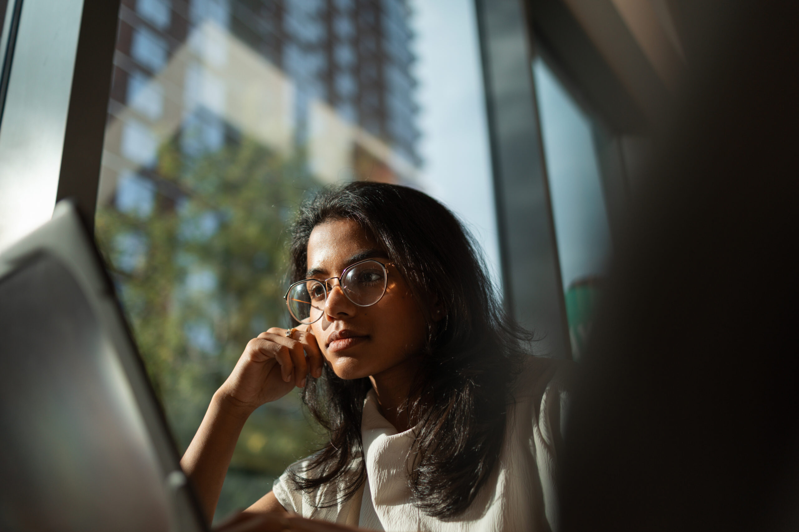 Young woman studying working on laptop against window