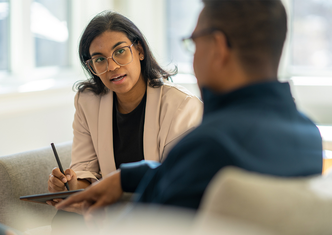woman writing on notepad talking to man