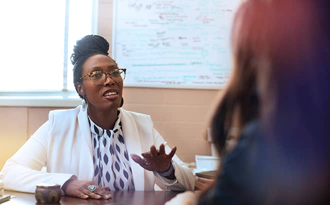 A woman in a white suit talking to a woman